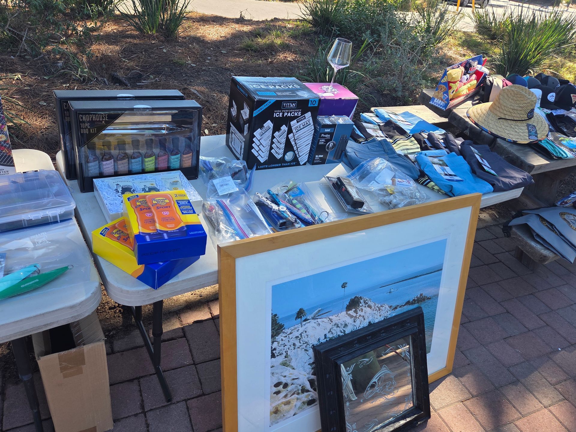 Table displaying various items for sale, including a printer, artwork, and clothing.