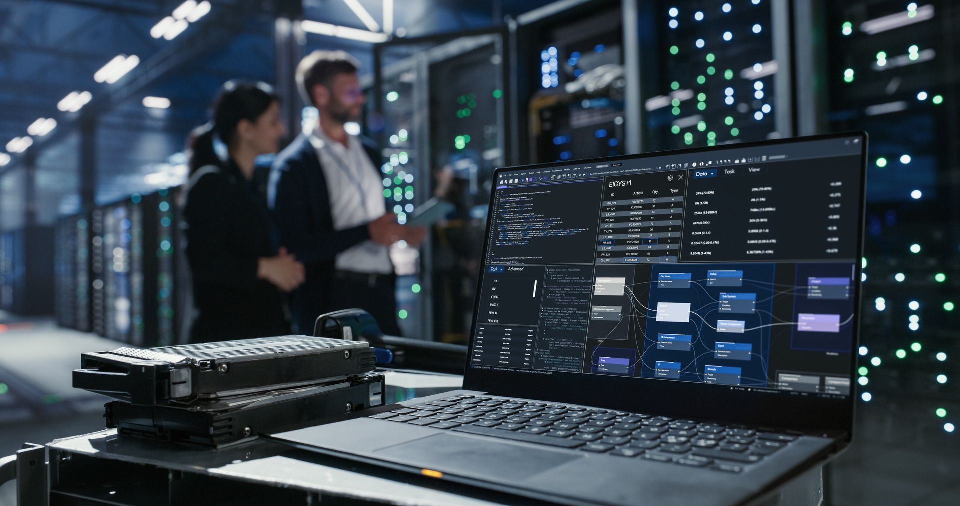 Two technicians reviewing a laptop in a server room with glowing rack lights