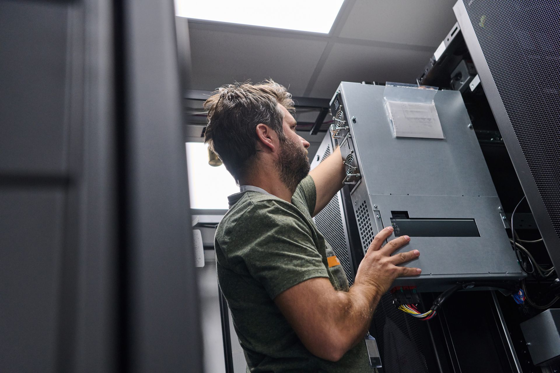 Technician inspecting server racks in a dark data center with blue LED lights