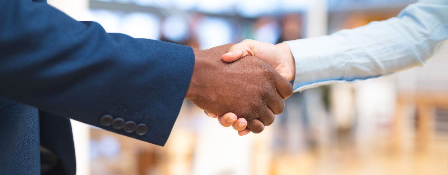 A close-up of two people shaking hands in a professional setting.