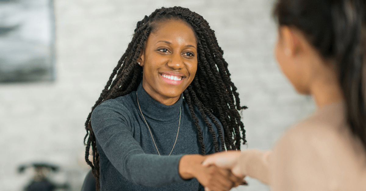 Two people shaking hands in a bright, modern office setting.