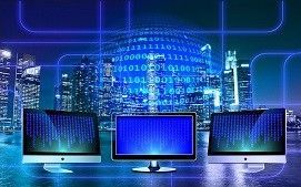 Three computer monitors display scrolling blue digital code against a background of a glowing, high-tech cityscape.