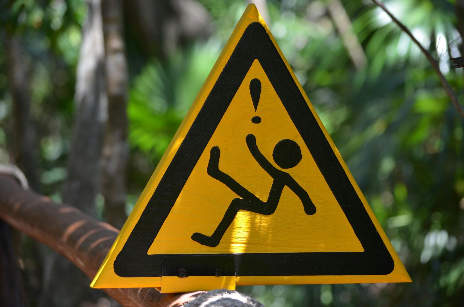 A yellow triangular warning sign with a black border shows a stick figure slipping, with an exclamation mark above.