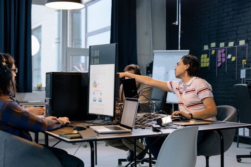 A group of people are sitting at a table in front of a computer.