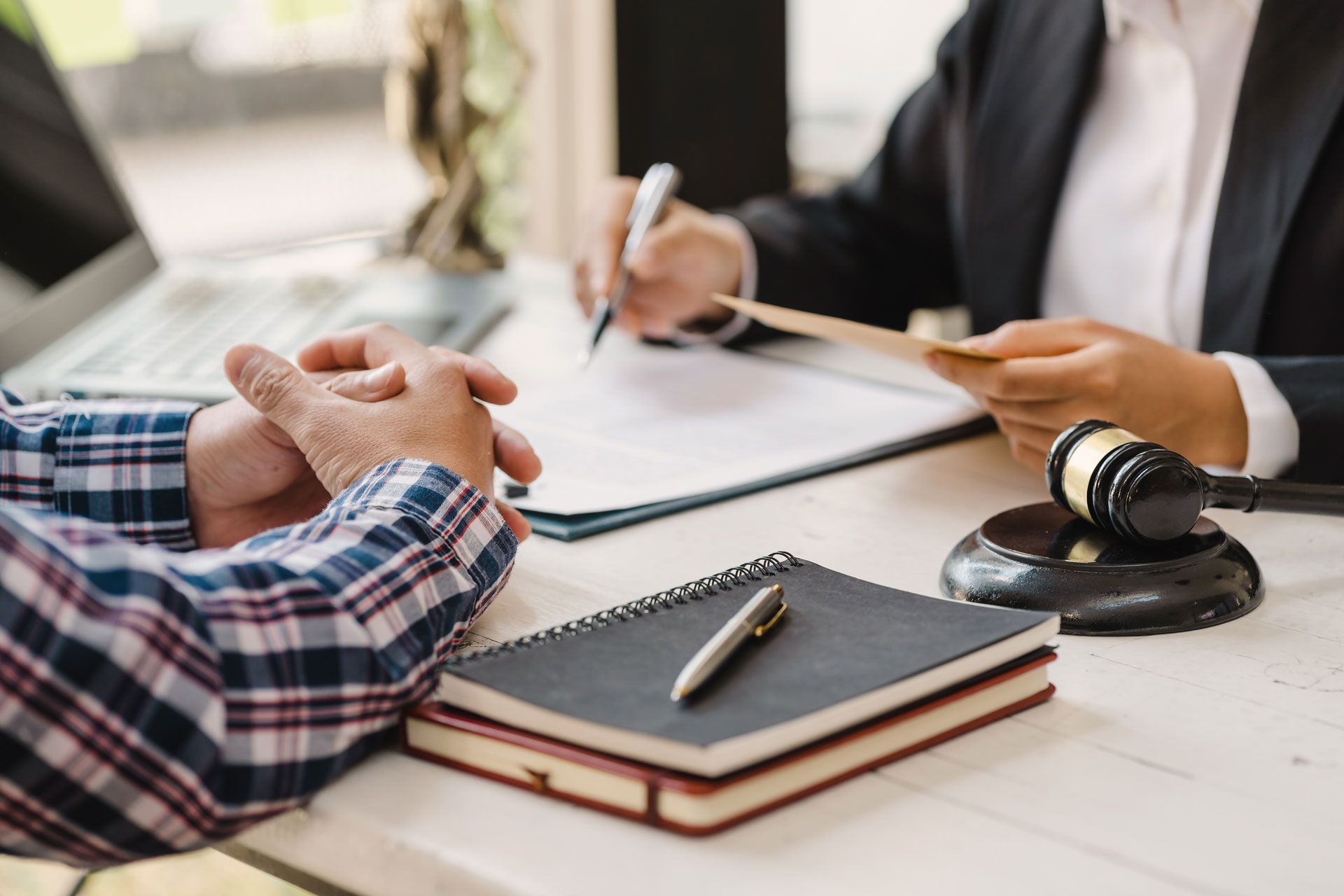Two people reviewing documents at a desk with a gavel and notebook in a legal meeting