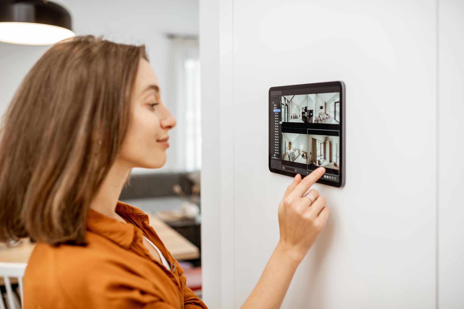 Woman using a wall-mounted smart home control panel in a bright room