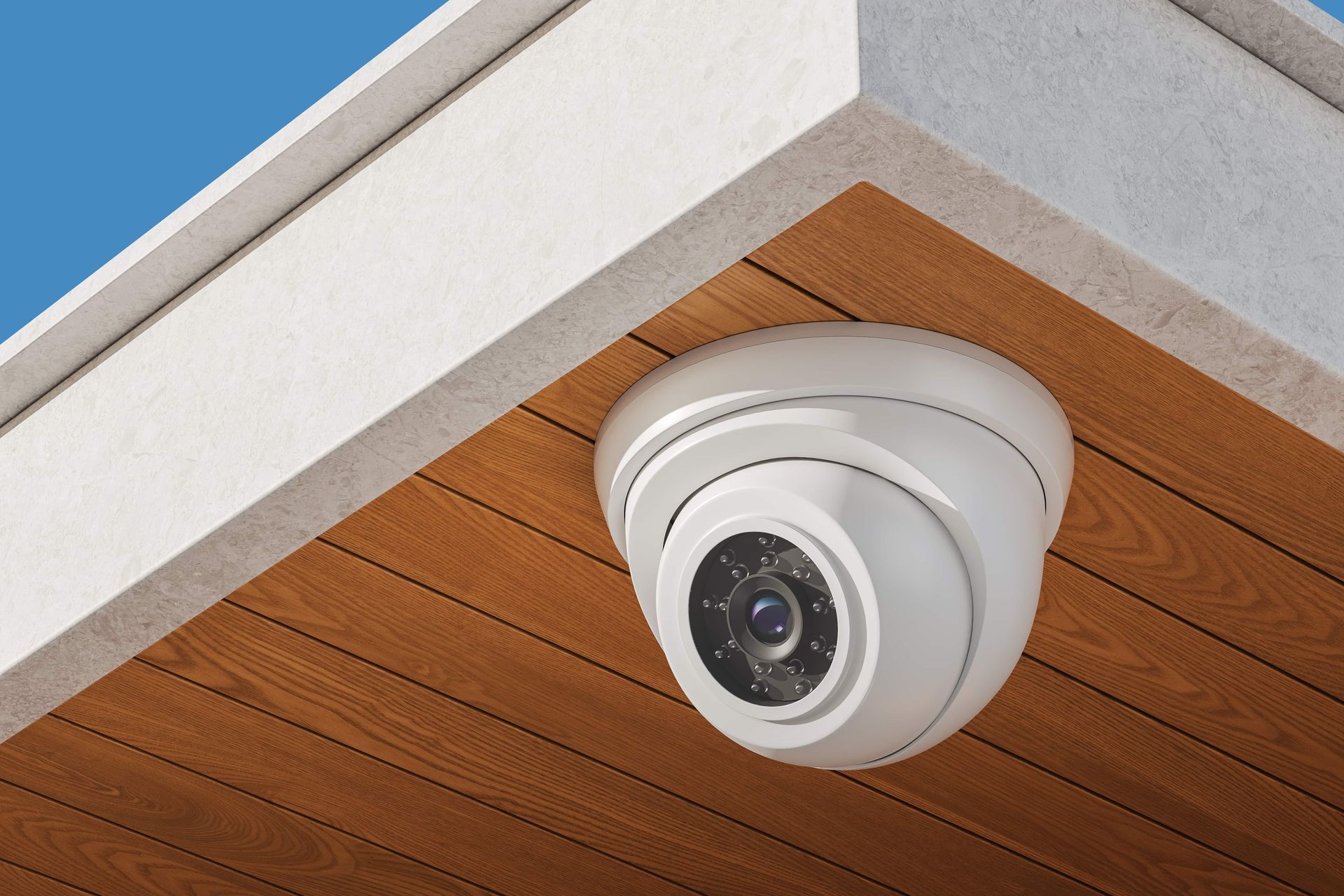 Dome security camera mounted under a wooden ceiling eave against a blue sky