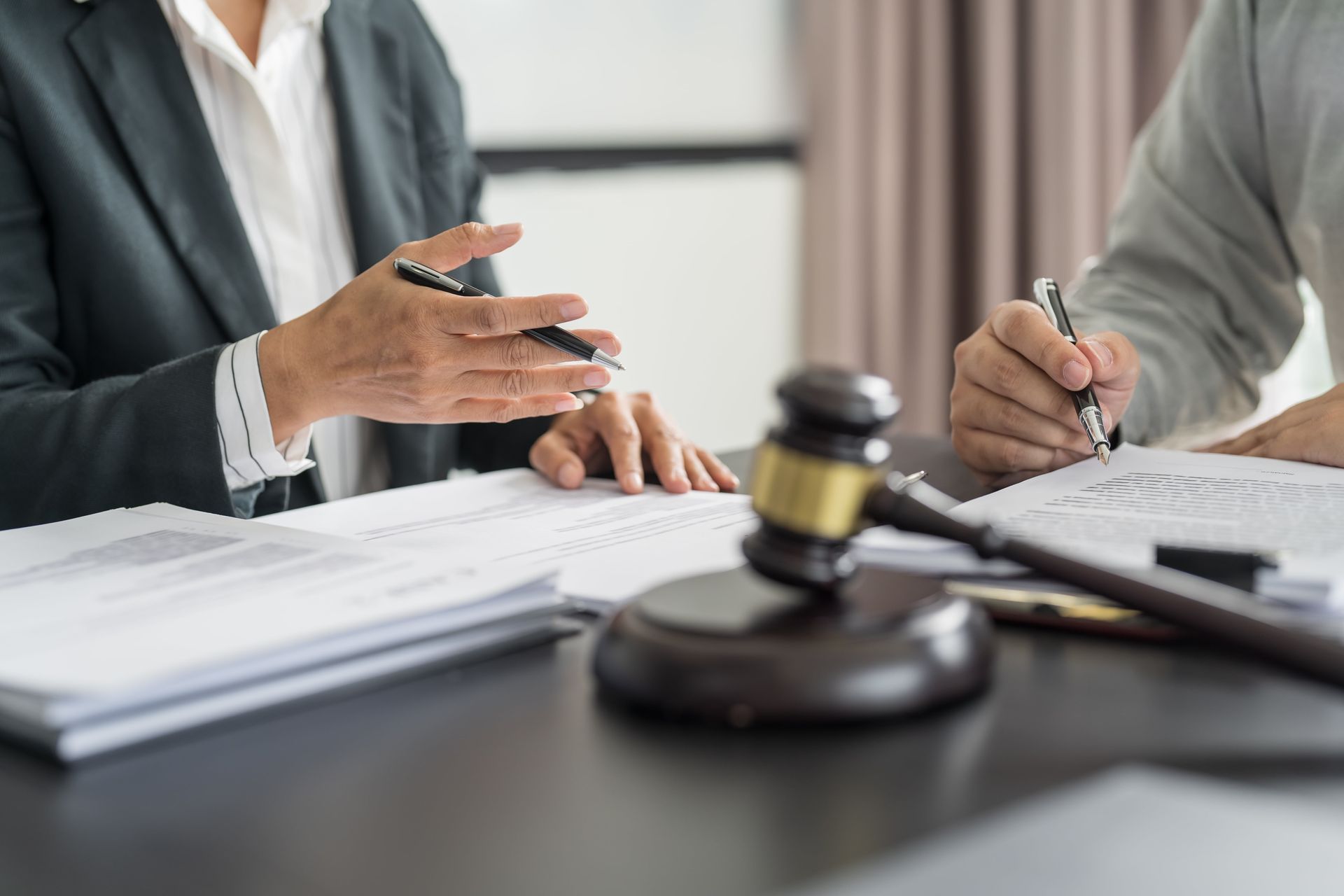Business meeting with two people discussing documents beside a judge’s gavel on a table
