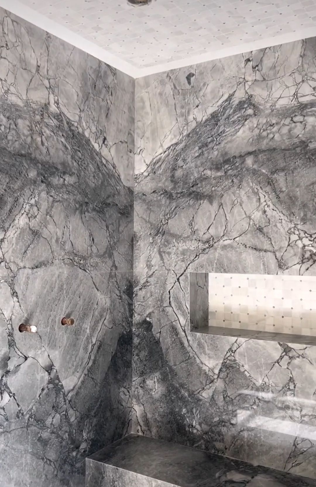 A bathroom with marble walls and a sink.