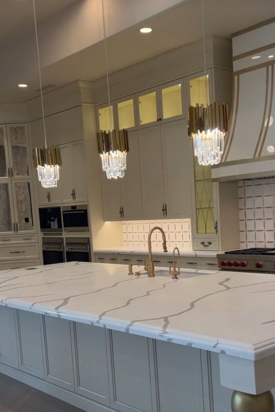 A kitchen with white cabinets , a large island , a sink , and a stove.