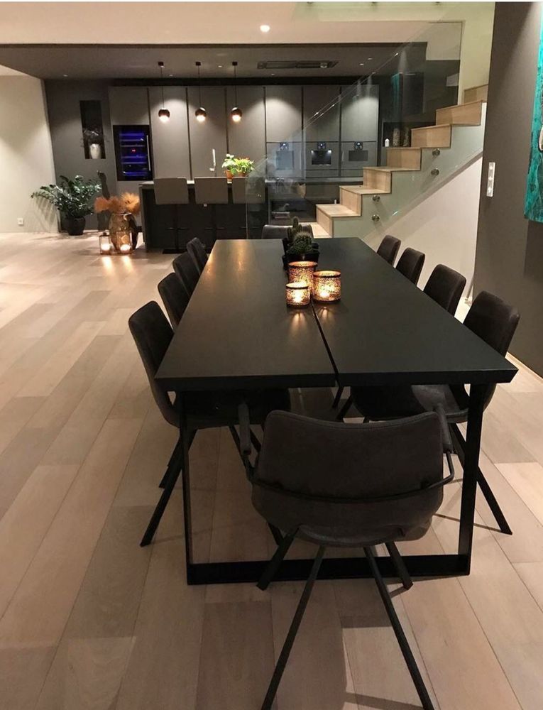 A dining room with a long black table and chairs