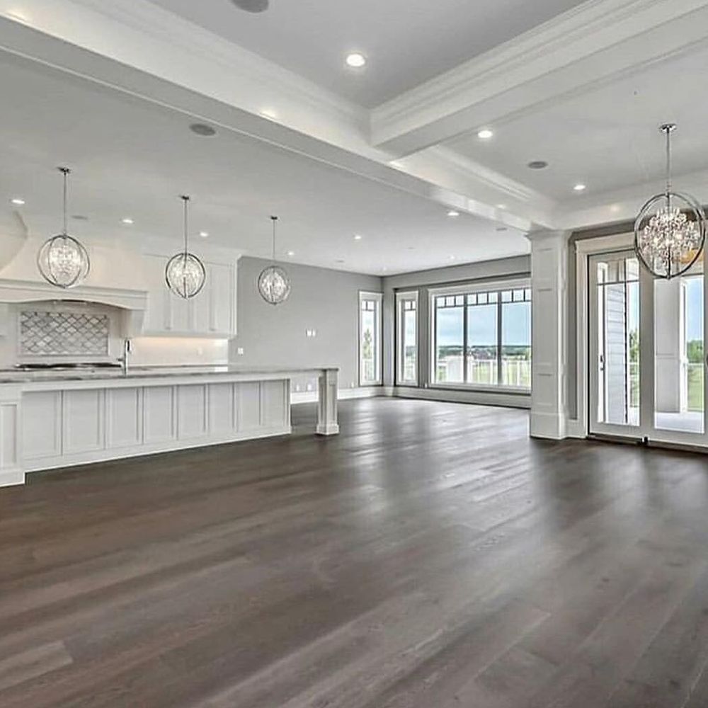 A large empty room with hardwood floors and white walls.