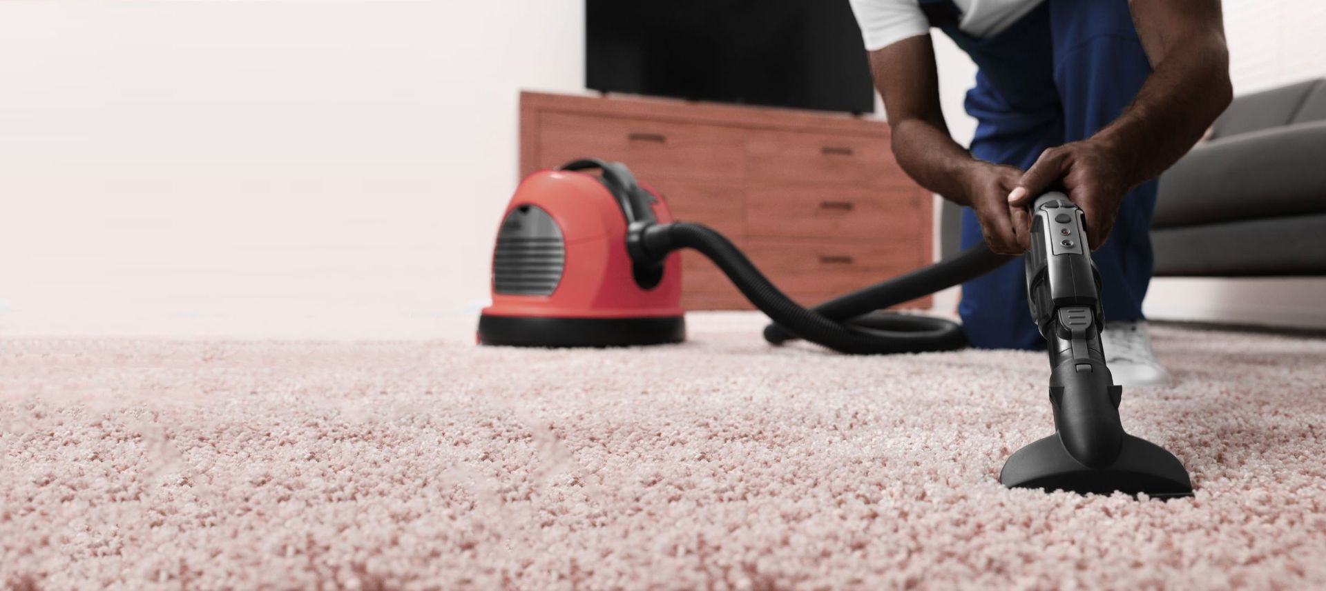 A person is cleaning a carpet with a vacuum cleaner.
