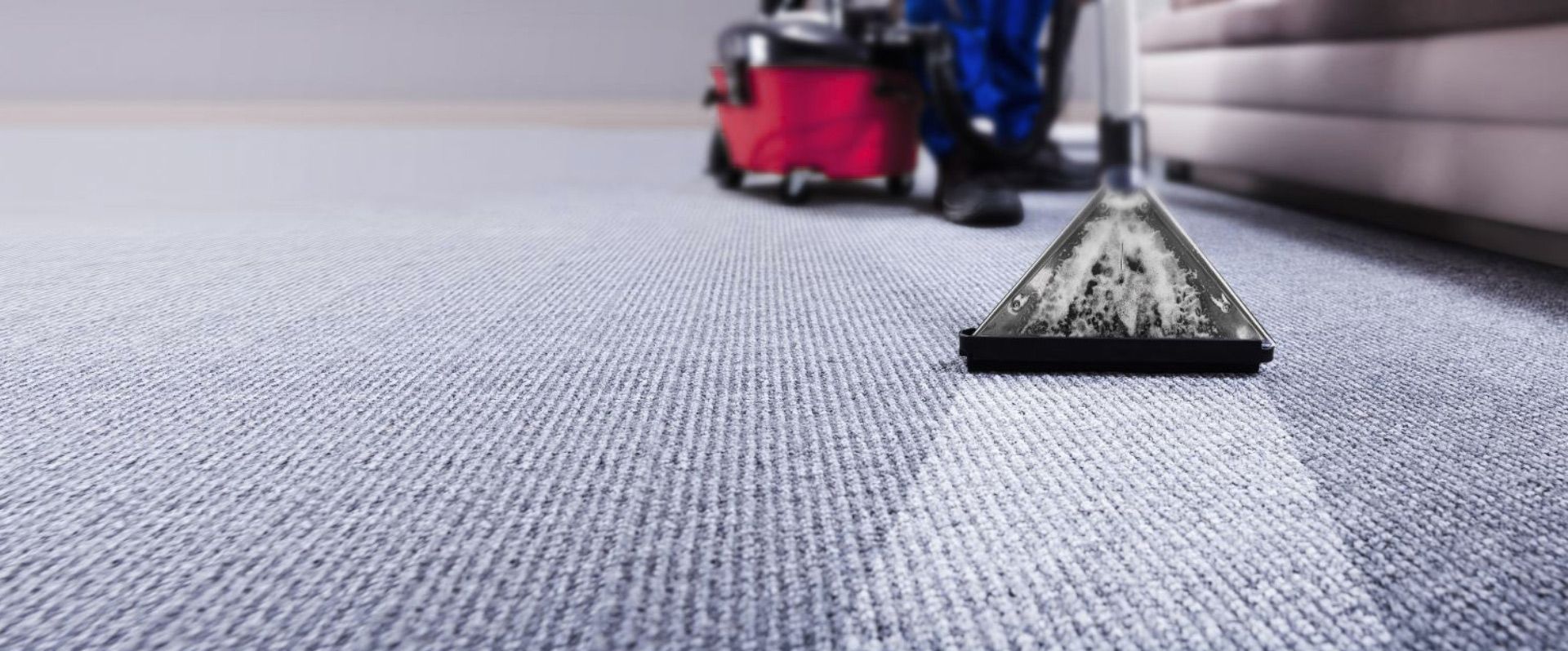 A man is using a vacuum cleaner to clean a carpet in a living room.