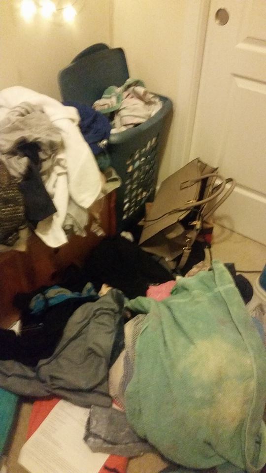 Clothes piled on floor, overflowing laundry basket, near a white door.