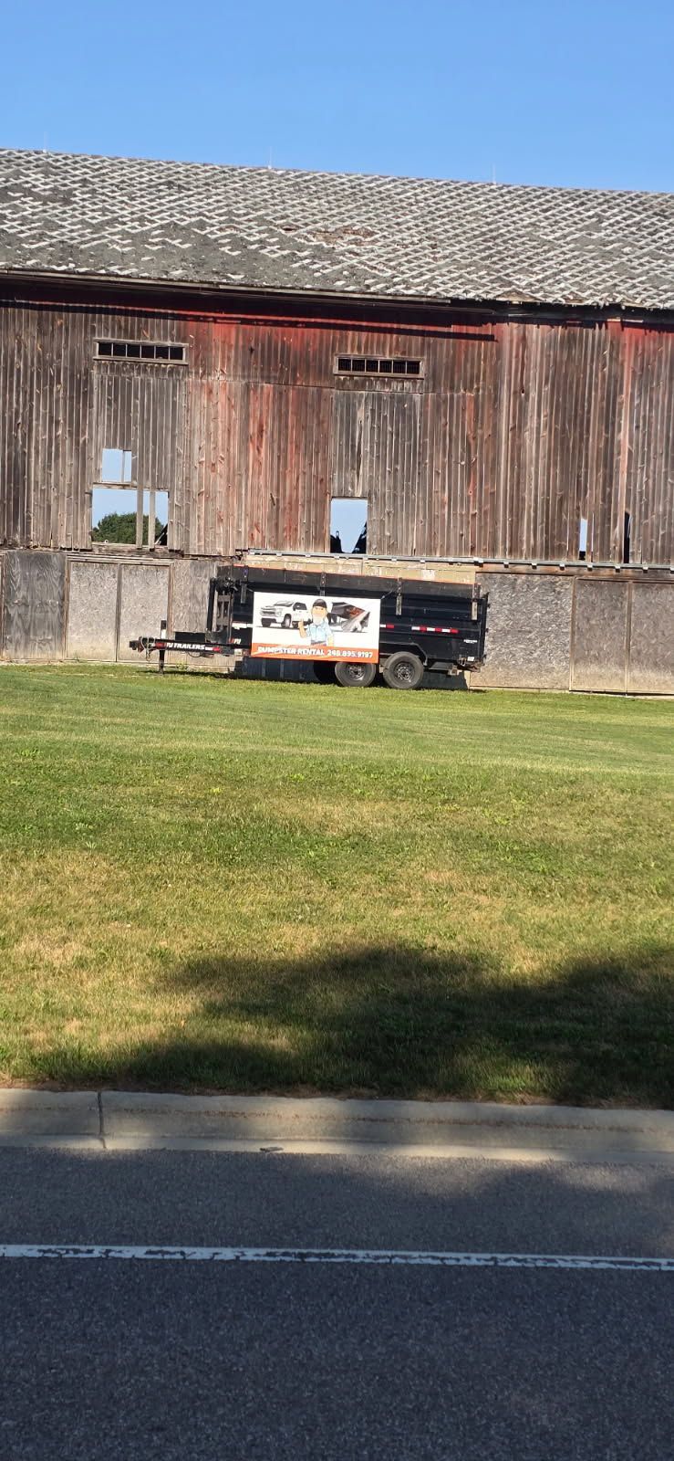 Rustic barn with weathered red siding and a small vintage truck parked on grass