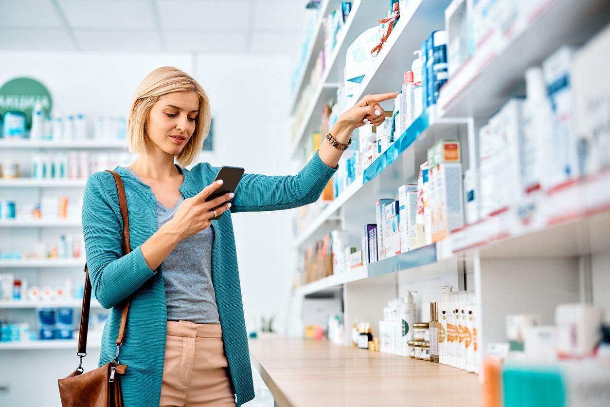 Una mujer mira su teléfono mientras está parada en una farmacia.