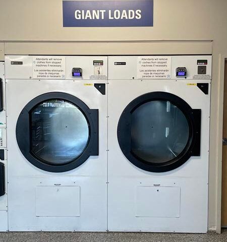 Two giant-load front-load dryers labeled “GIANT LOADS” in a laundromat.