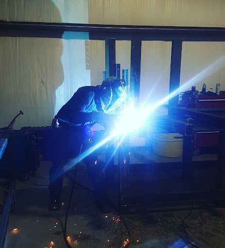 A man is welding a piece of metal in a dark room