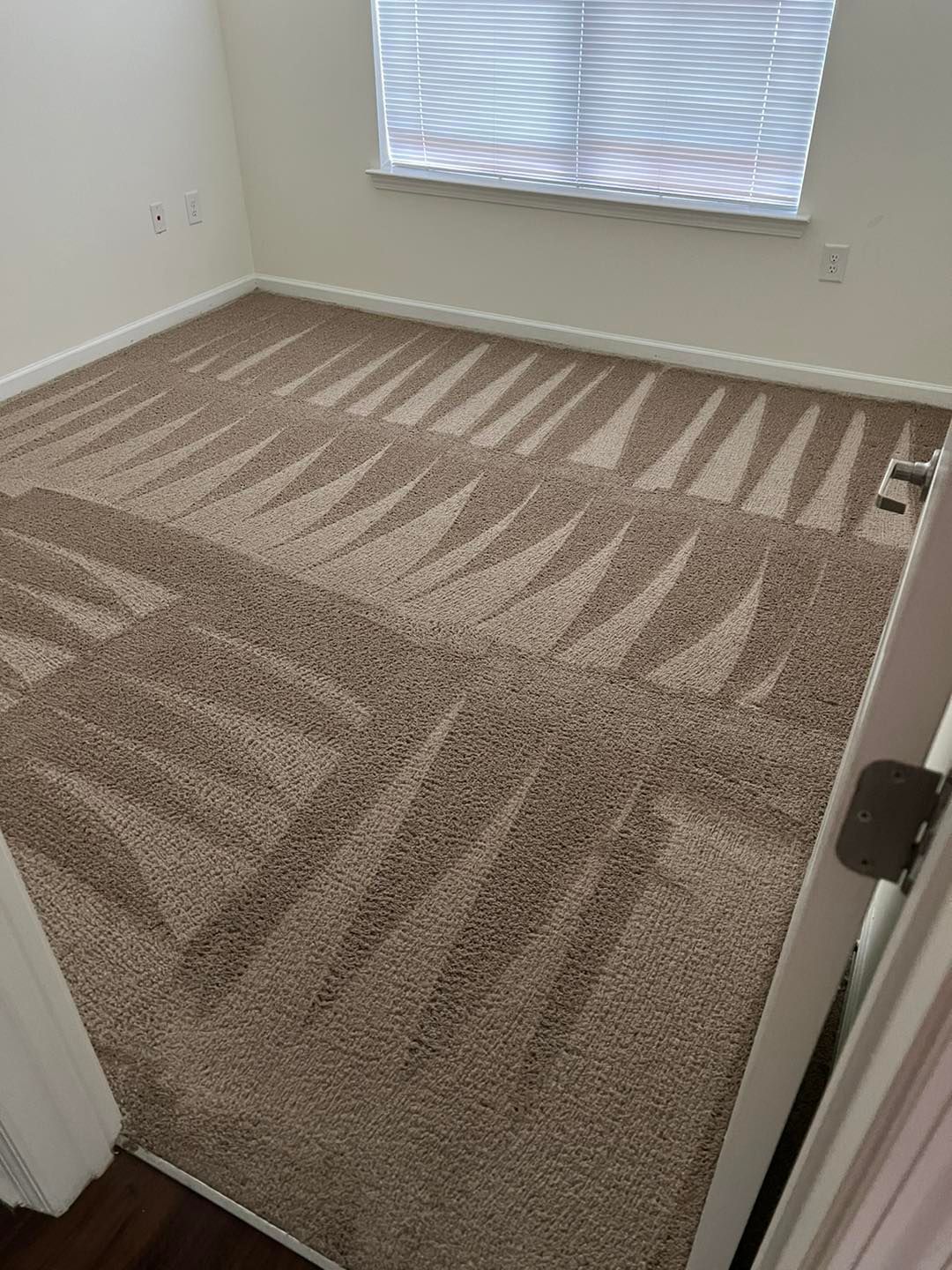 A bedroom with a carpeted floor and a window.