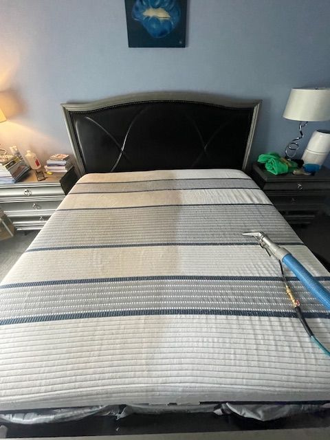 A mattress is being cleaned in a bedroom with a vacuum cleaner.