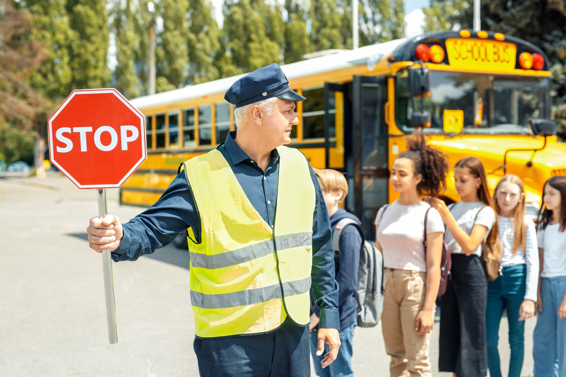 A man is holding a stop sign in front of a school bus.