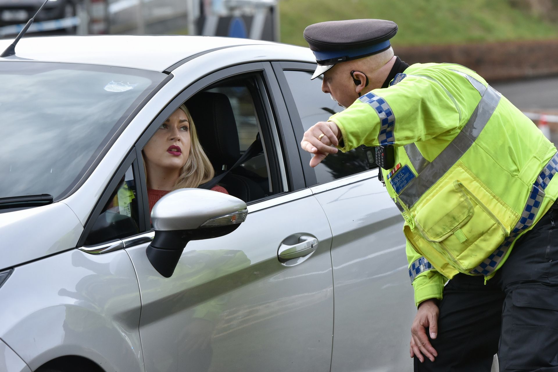 A police officer is talking to a woman in a car.