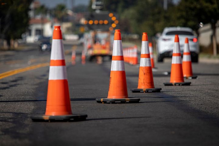 A row of orange and white traffic cones on the side of a road.