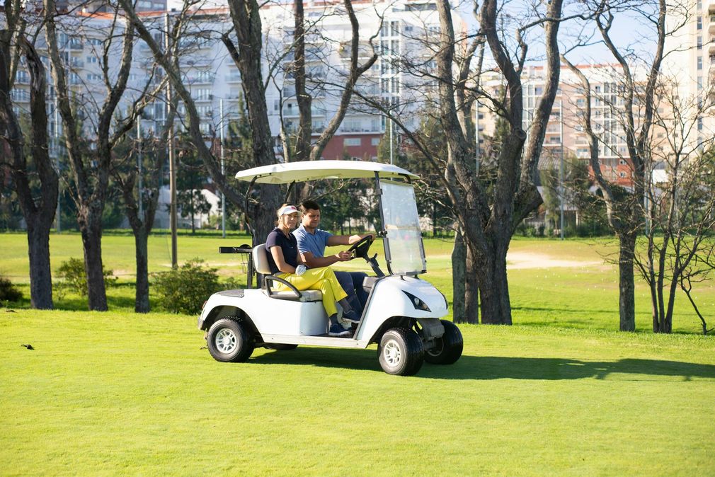 Two people are riding a golf cart on a golf course.