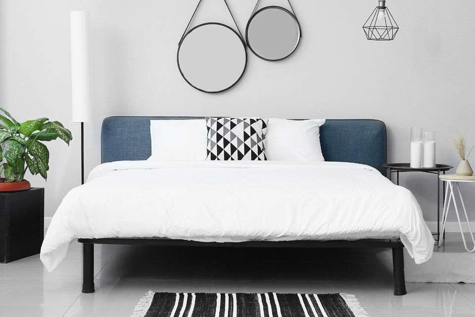A bedroom with a bed and two mirrors on the wall.