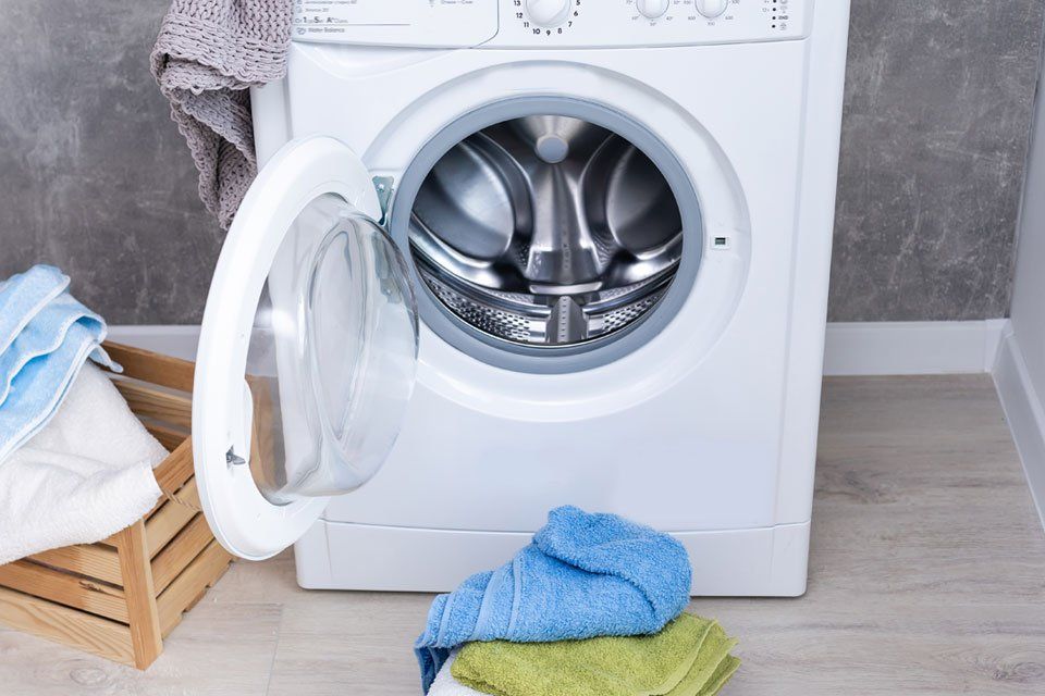 A washing machine with its door open and clothes in it.