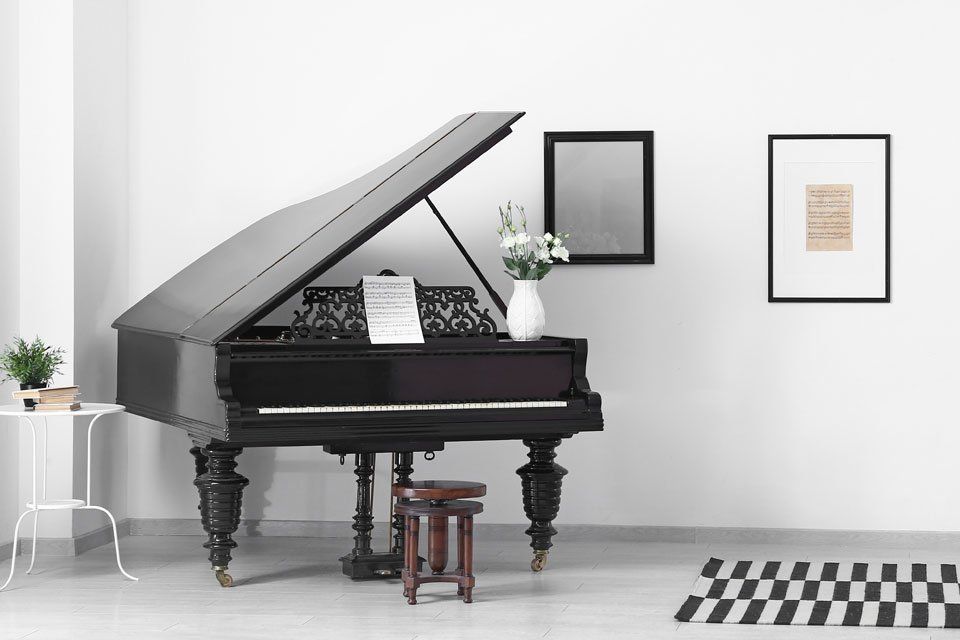 A black grand piano is sitting in a living room next to a stool.