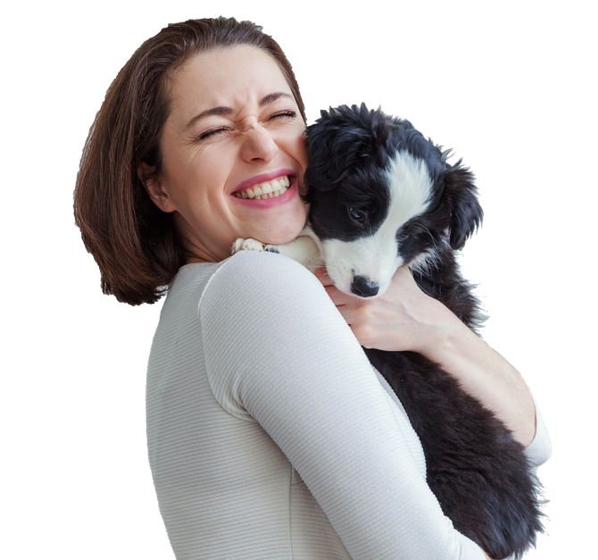 A woman is holding a black and white puppy and smiling