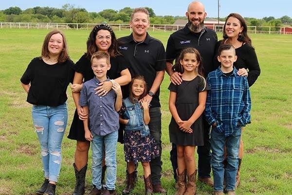 A large family is posing for a picture in a grassy field.