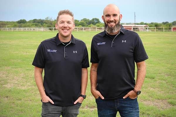Two men are standing next to each other in a field.
