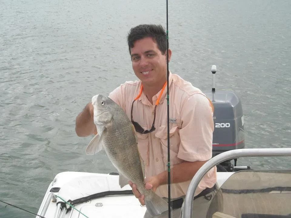 A man is holding a large fish on a boat.