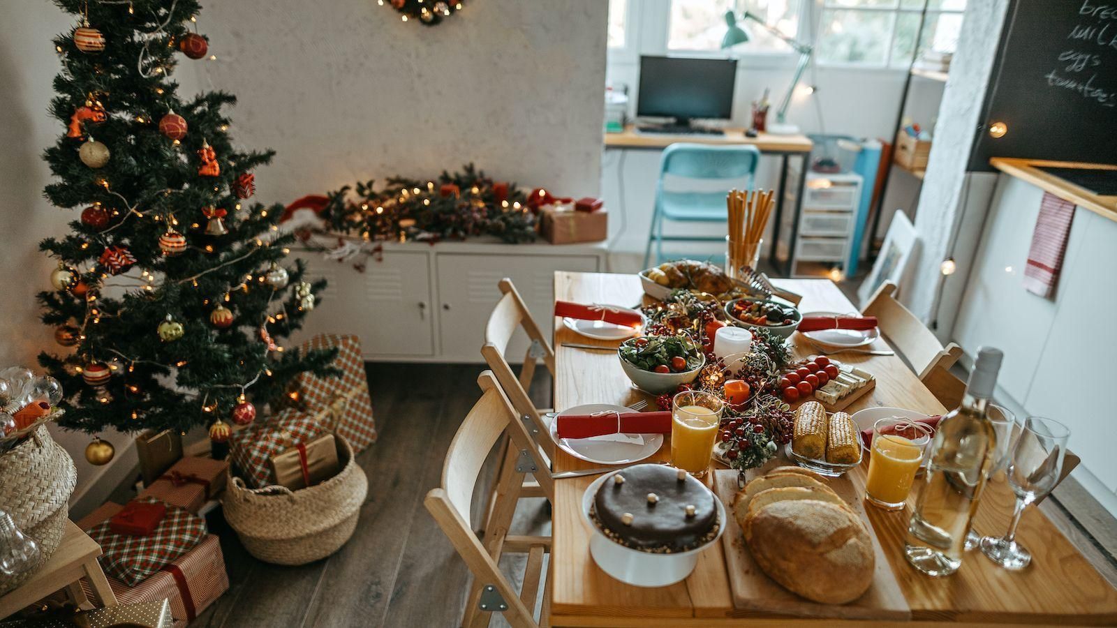 Festive dining table set for Christmas beside a decorated tree and garland