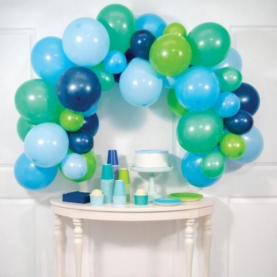 Blue and green balloon arch over a white table with party cups and plates