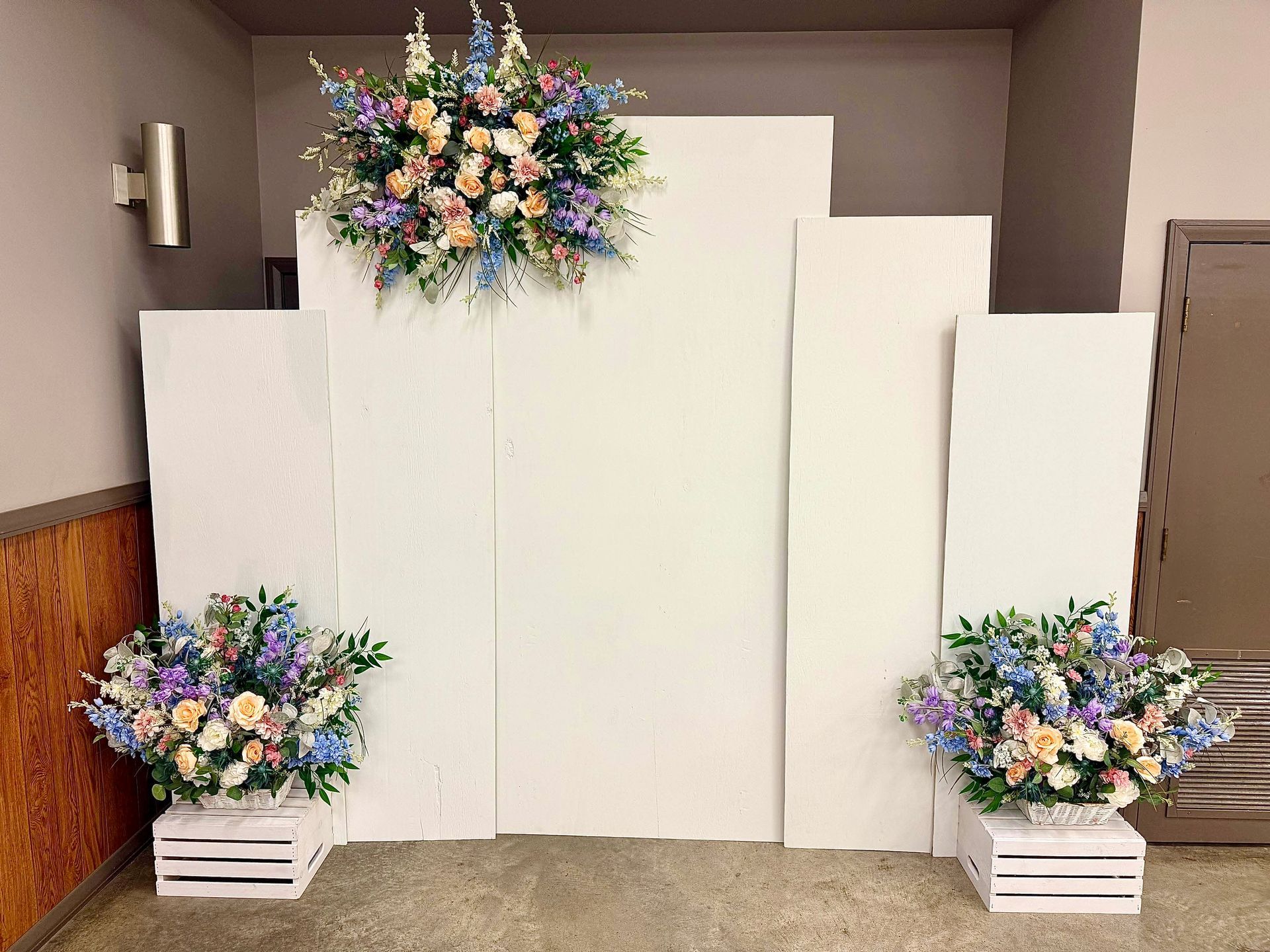 White floral backdrop with pastel flower arrangements in a room.