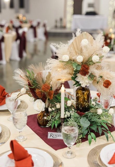 Elegant table centerpiece with cream and rust flowers, candles, and greenery at a formal event