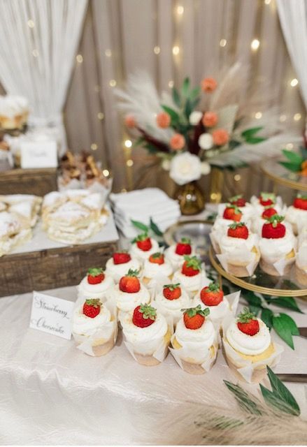 Dessert table with strawberry-topped cupcakes and cake, arranged on a decorated buffet table.