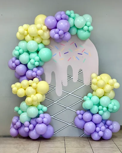 Pastel balloon arch around a pink ice cream-shaped backdrop on a tiled floor