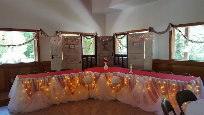 Decorated event stage with draped white table, warm string lights, and garlands in a hall