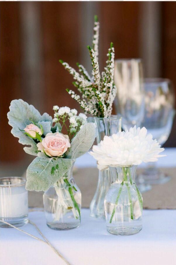 Small glass vases with white and pink flowers on a table at a formal event