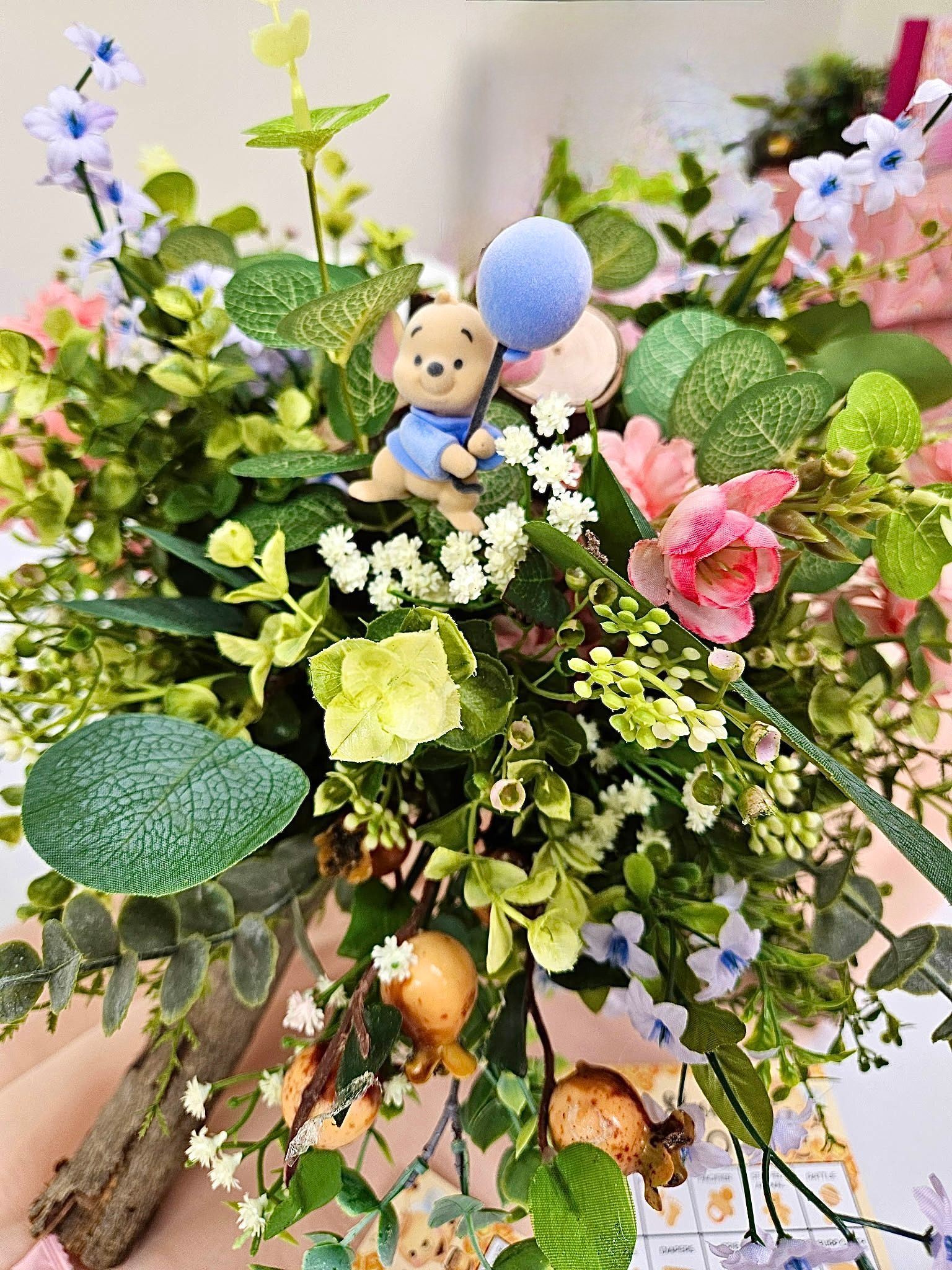 Pastel floral bouquet with a small teddy bear and balloons in a decorative arrangement