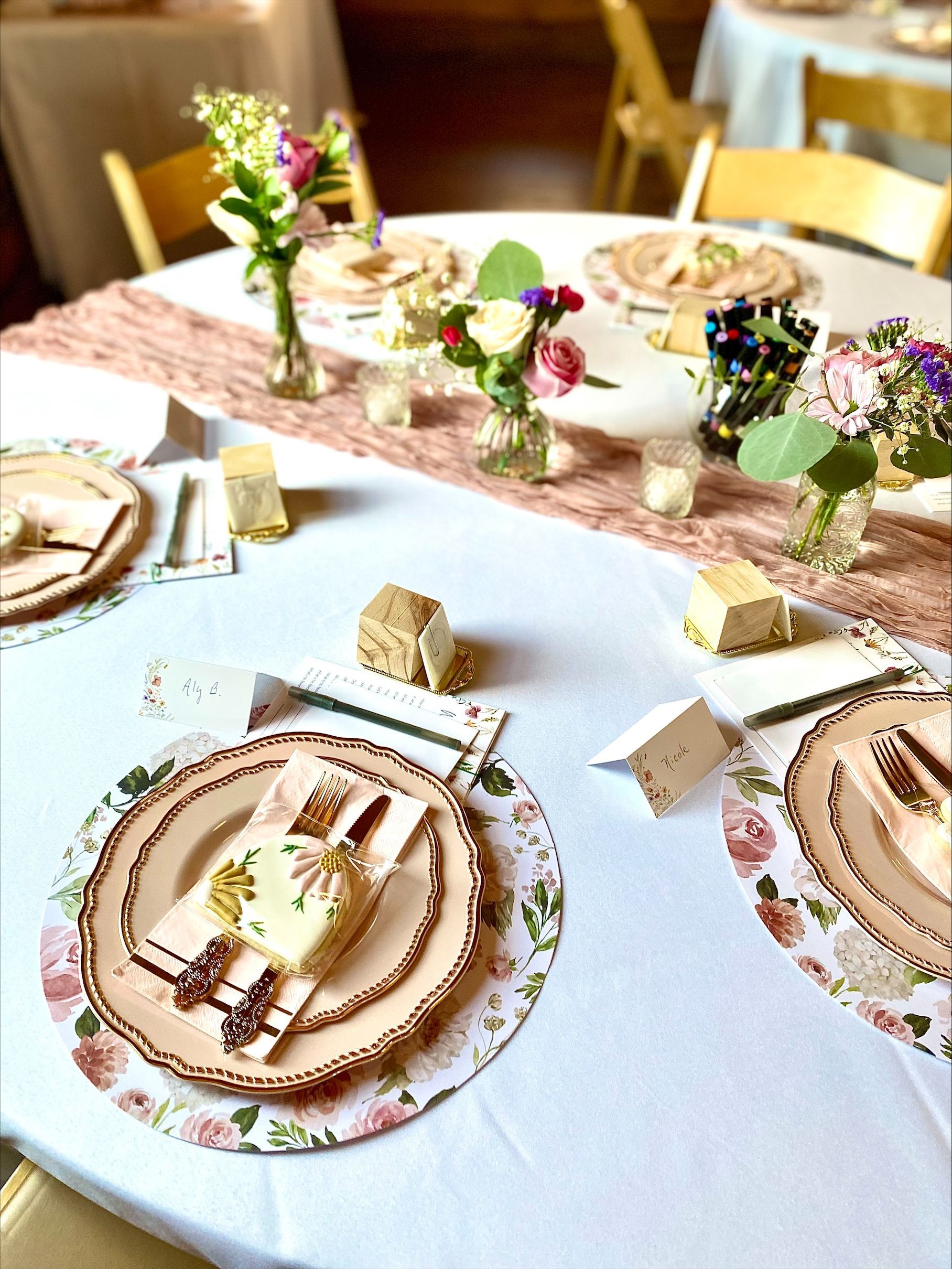 Elegant dining table set with floral placemats, folded napkins, and small floral centerpieces