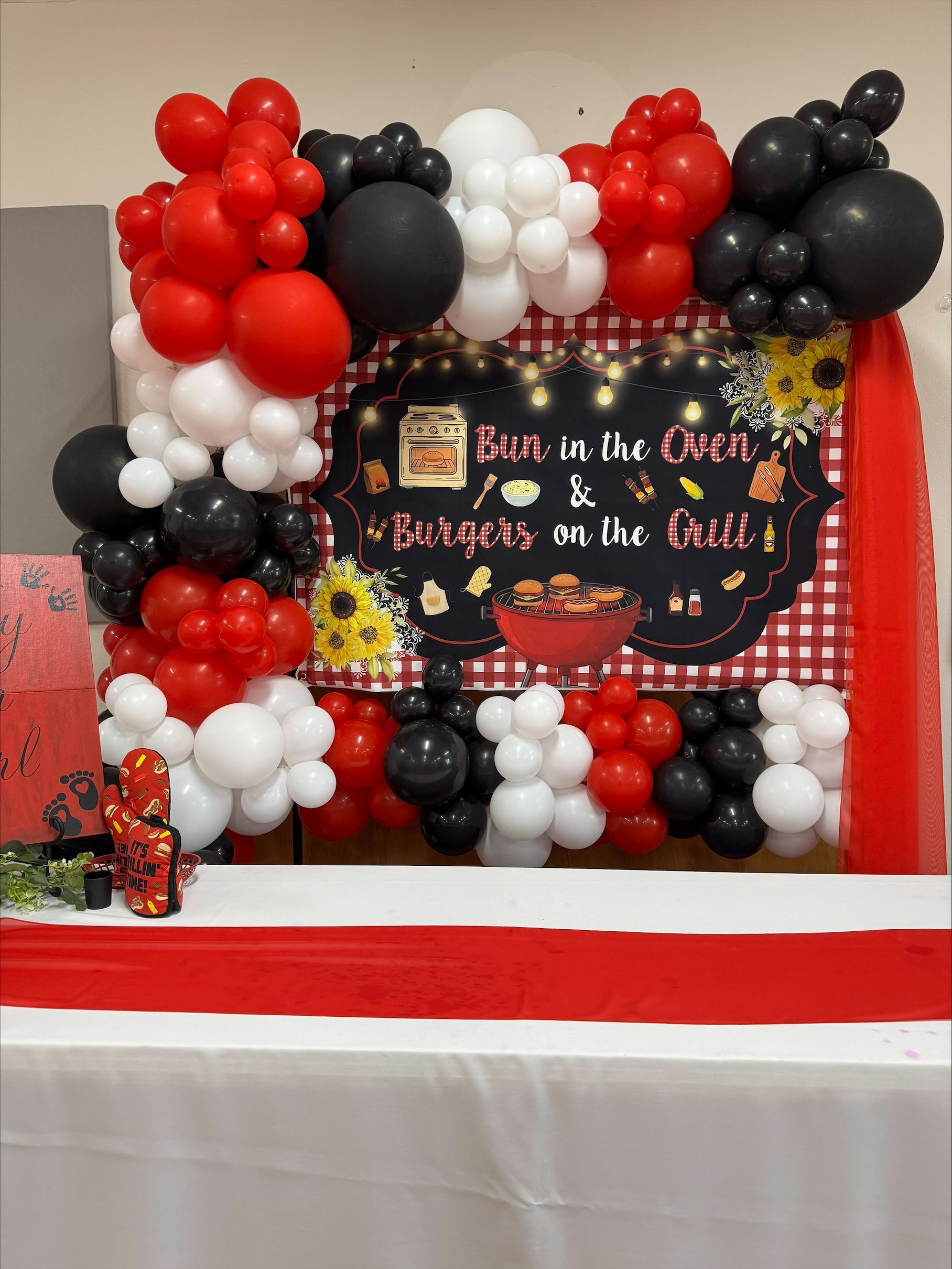Black, red, and white balloon backdrop with a “Back to the 90s” party sign above a table.