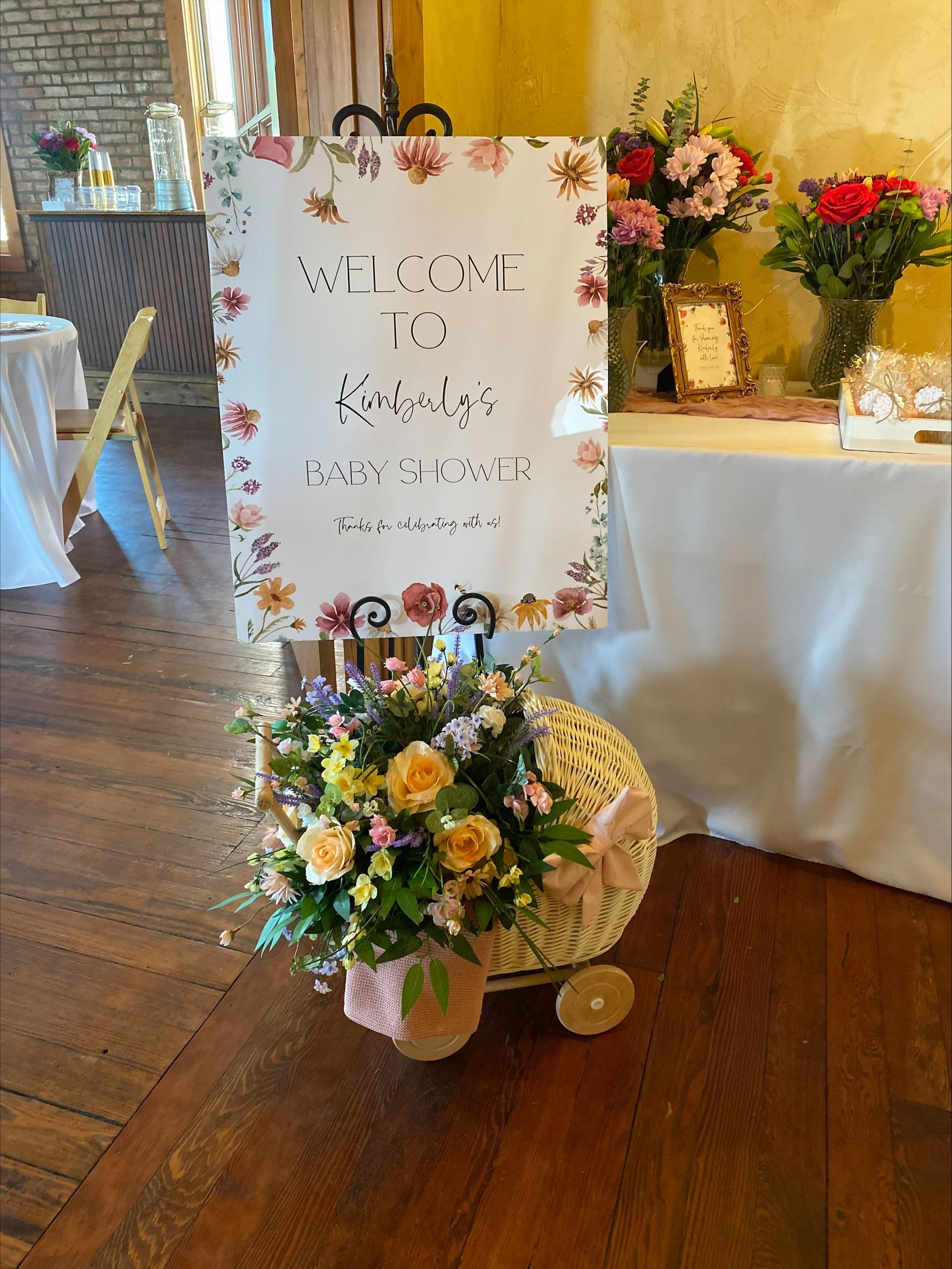 Wedding welcome sign with pastel floral decorations beside a table of flowers in a rustic hall