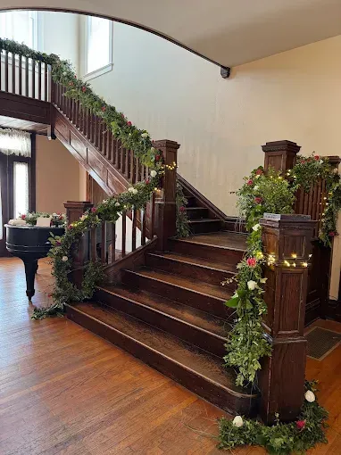 Elegant indoor staircase with dark wood railings and green garlands in a bright foyer