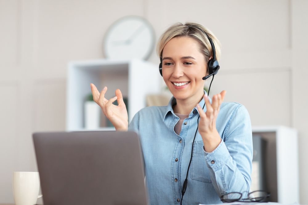 Woman Wearing a Headset Smiles and Gestures During a Video — Pacific Telephone & Data In Cardiff, NSW